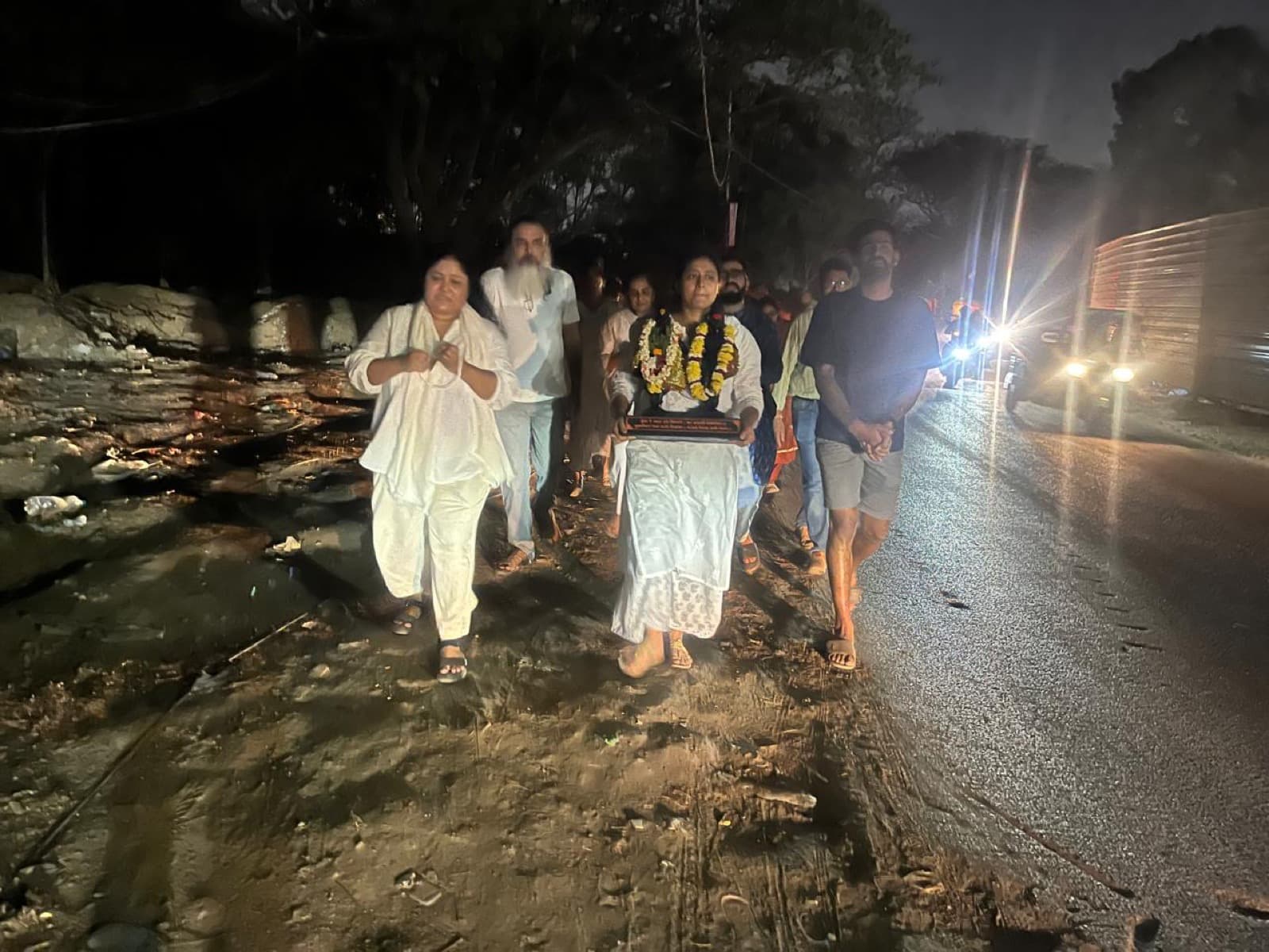 A small group walking with a garlanded murti