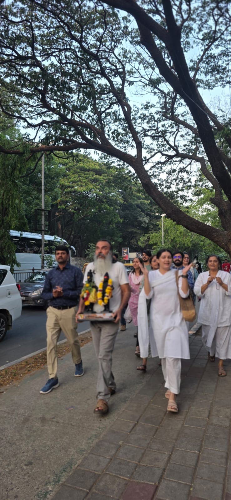 Two small murtis of Sri Vitthal and Mata Rukmini, garlanded and dressed, held quietly before the first walk